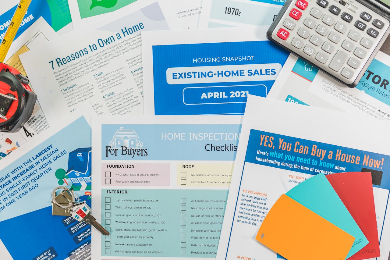 about-01 Flat lay of real estate brochures, checklists, and a calculator for home buying.