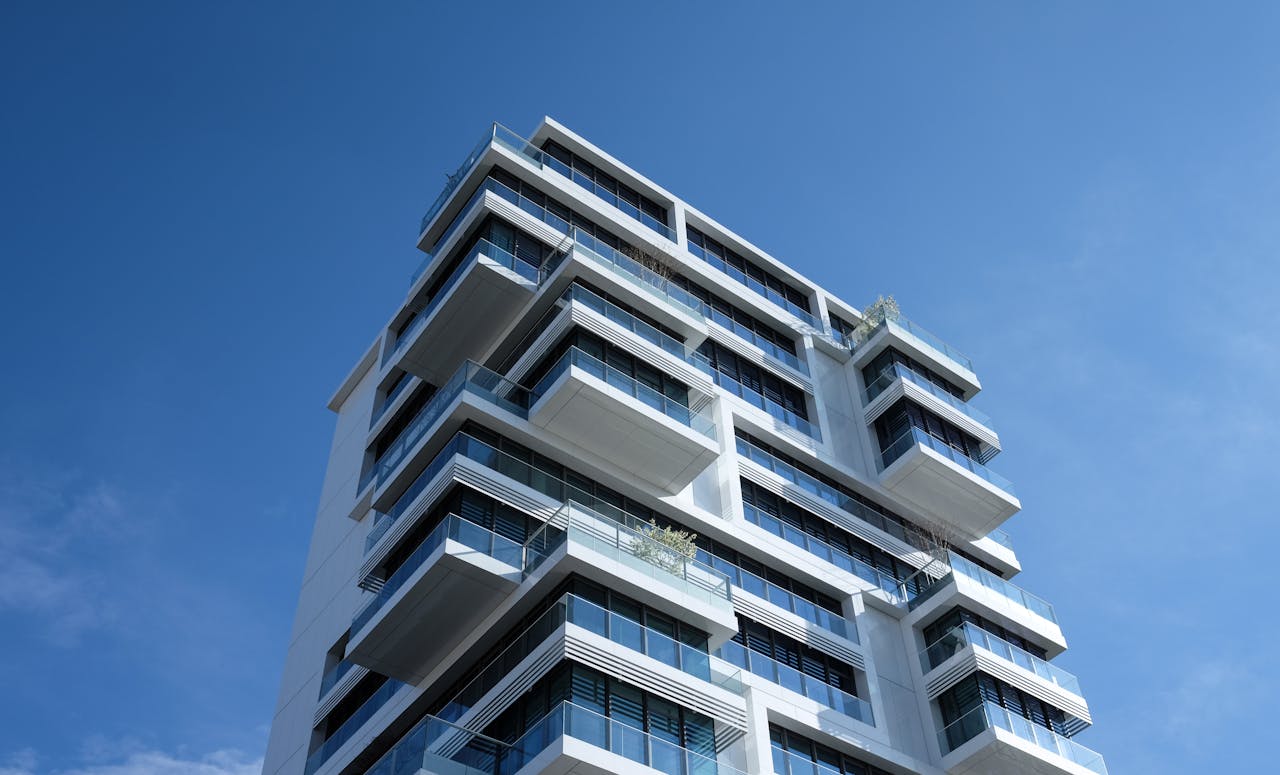 why-choose-us Striking low-angle shot of a modern condominium with unique balcony design and clear blue sky.
